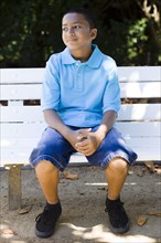 Smiling mixed race boy sitting in park