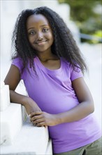 Smiling Black girl leaning on wall