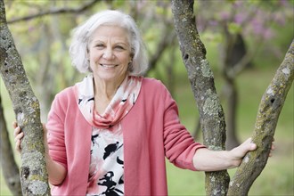 Smiling senior Caucasian woman standing near tree