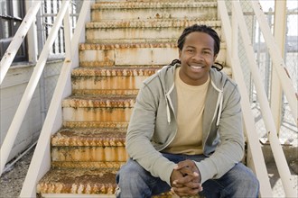Smiling Black man sitting on staircase