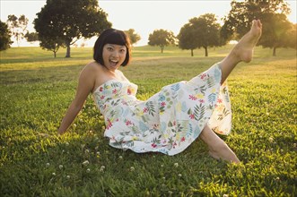 Asian woman kicking up foot in grass