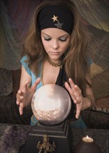 Woman dressed at fortune teller looking into crystal ball