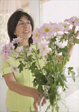 Senior woman arranging flowers in vase