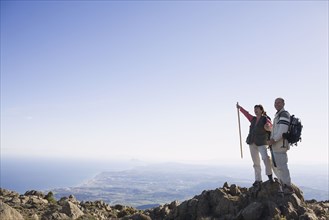 Senior couple standing on cliff with backpacks