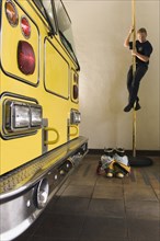 Male firefighter sliding down pole