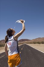 Mixed Race female runner pouring water on face
