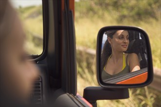 Reflection of Hispanic woman in side mirror of jeep