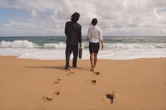 Businessman and businesswoman walking towards ocean