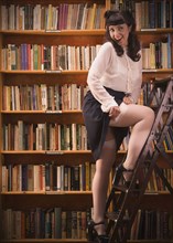 Woman in retro clothing on library ladder