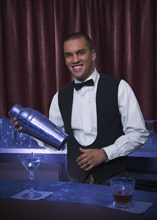 Hispanic bartender making cocktail