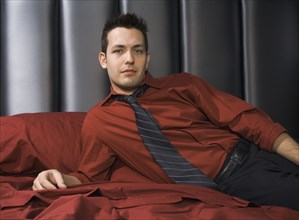 Man wearing shirt and tie on bed