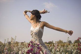 Asian woman with arms outstretched in meadow