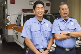 Asian male paramedics in front of ambulance