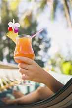 Asian woman with cocktail in hammock