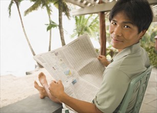 Asian man reading newspaper