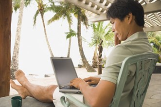 Asian man typing on laptop