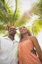 African American couple hugging under palm tree