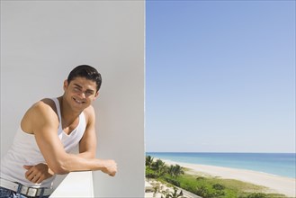 Hispanic man leaning on balcony railing