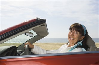 Senior Hispanic woman driving convertible car