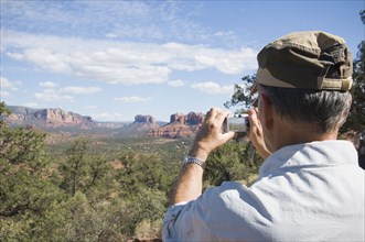 Senior man taking photograph of desert landscape