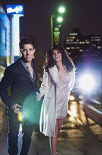Elegant couple walking on urban street at night