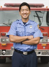 Asian firefighter next to fire truck