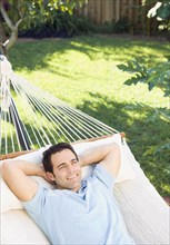 Mixed race man relaxing in hammock