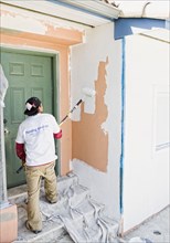 Latin man painting wall near front door