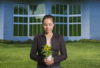 Mixed race woman holding flowers in pot