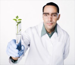 Hispanic scientist holding test tube containing sprout