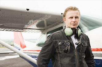 Caucasian pilot standing near small airplane