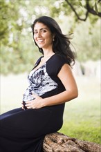 Mixed race pregnant woman sitting outdoors