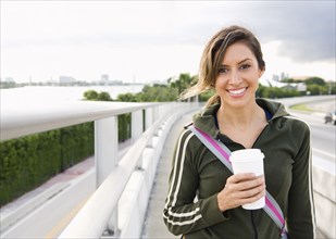 Hispanic woman walking outdoors with coffee