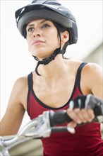 Hispanic woman in helmet riding bicycle