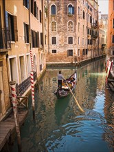 Gondolier rowing gondola in canal