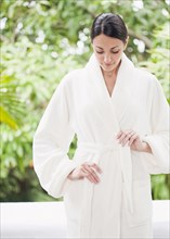 Caucasian woman tying bathrobe