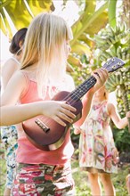 Caucasian girl playing ukulele outdoors