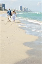 Caucasian couple walking on beach