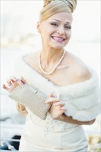 Smiling Hispanic bride holding purse