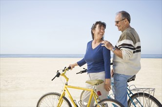 Couple standing with bicycles on beach