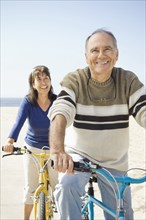 Couple sitting on bicycles on beach