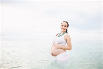 Pregnant Caucasian woman standing in water