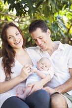 Caucasian couple holding baby outdoors