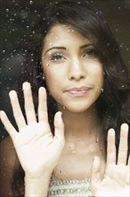 Hispanic woman looking out rainy window