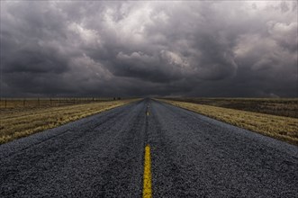 Paved road under cloudy sky in remote landscape