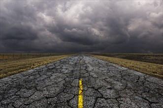 Cracked road under cloudy sky in remote landscape