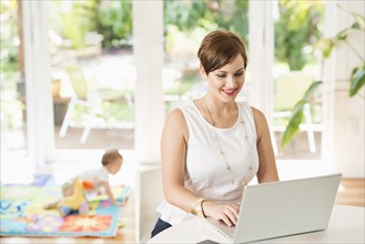 Caucasian mother using laptop at counter
