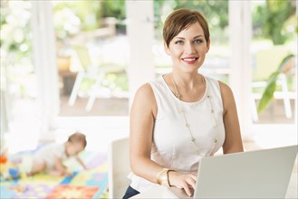 Caucasian mother using laptop at counter
