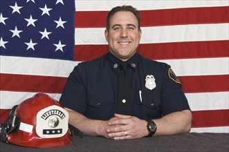 Caucasian firefighter smiling near American flag