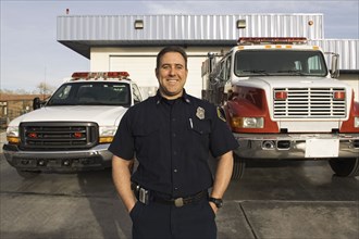 Caucasian firefighter smiling near fire trucks